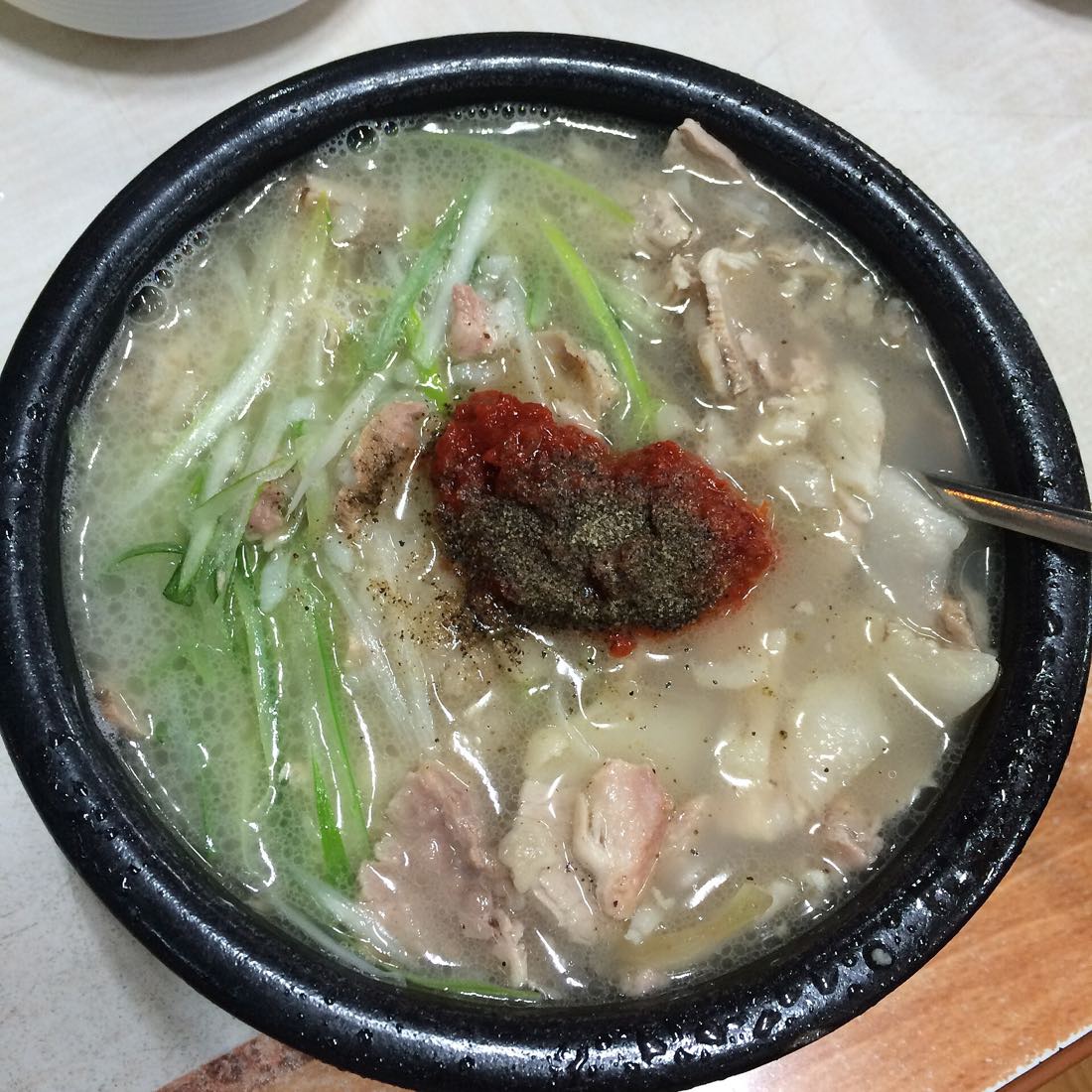 A steaming bowl of dwaeji gukbap with dadaegi seasoning on top